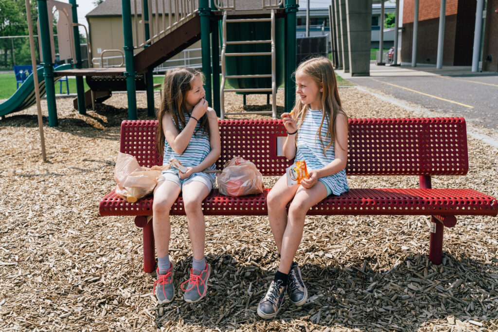 Students eating food received from Bite2Go on a playground bench