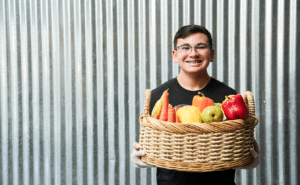 A young volunteer holding a basket of fruits and vegetables