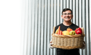 A young volunteer holding a basket of fruits and vegetables