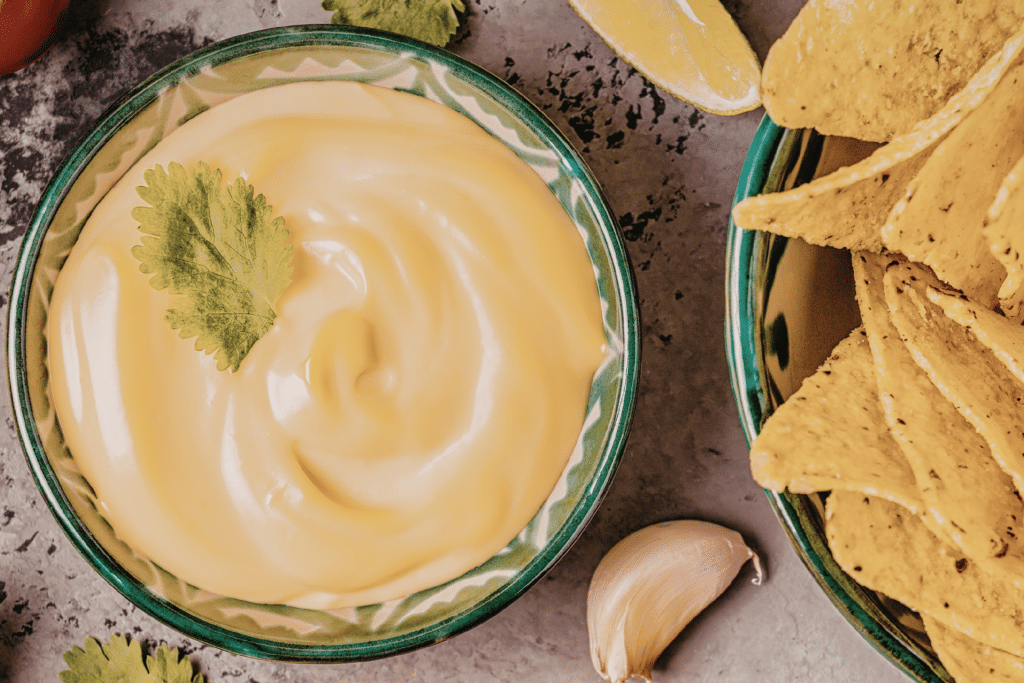 Nacho cheese sauce in a dish next to tortilla chips