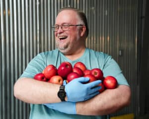 Smiling volunteer holding a large bund of apples.